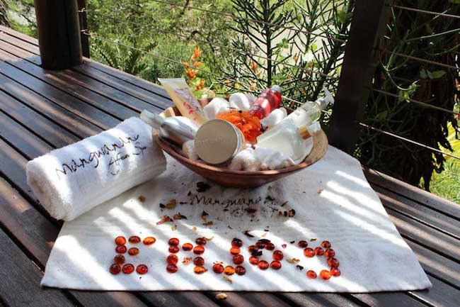 A Mangwanani Spa sundeck feature with white towels, relaxing spa products and red pebbles