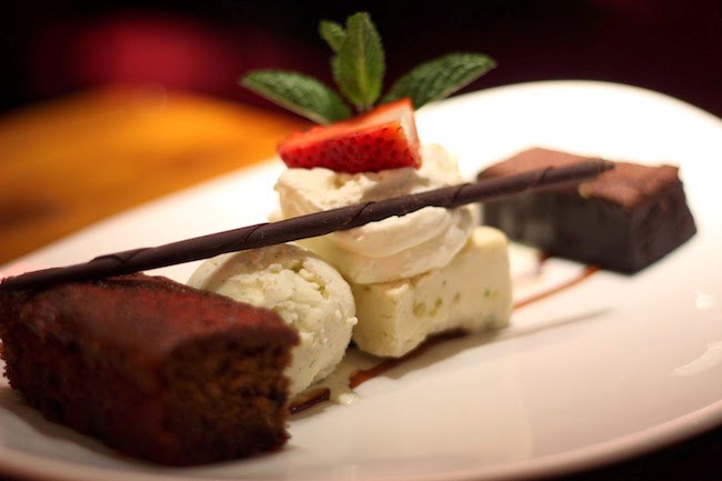 A gourmet chocolate dish with ice cream, cake and strawberries on a white plate